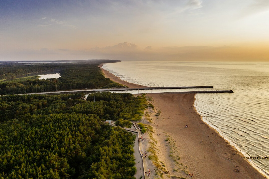 Wide sandy Baltic Sea beach in Poland with dunes and pier at sunset